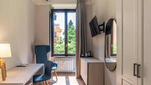 Una habitación pequeña con escritorio, silla y un espejo grande.