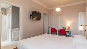 Ein Hotelzimmer mit Bett, Schreibtisch mit Stuhl, Fernseher und Lampe.