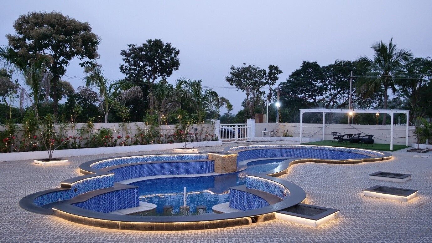 A pool area with multiple interconnected pools, surrounded by a paved walkway and palm trees.