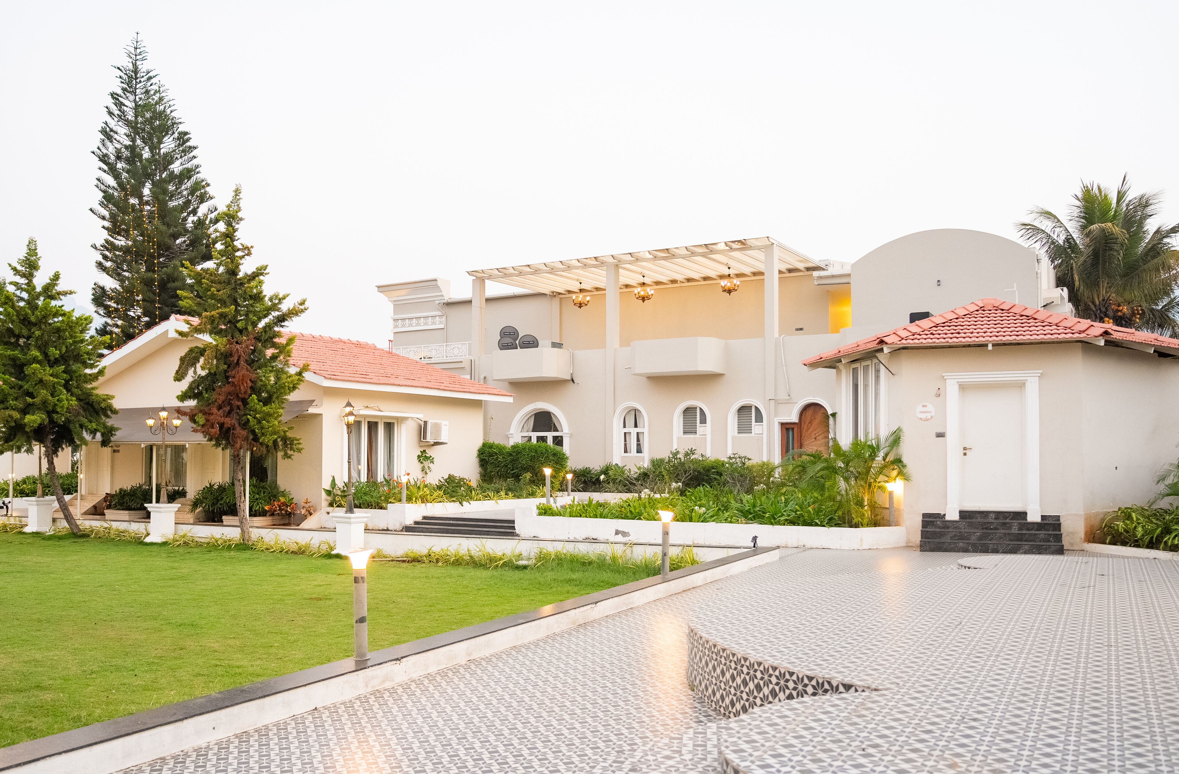 A modern building with a tiled courtyard, a covered outdoor seating area, and a well-maintained lawn.