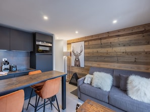 A modern kitchen with dark cabinets, a wooden wall, and a large deer painting. - Cozy apartment for 4, near slopes in Courchevel (Courchevel 1650)
