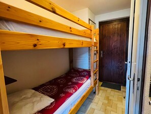A bunk bed room with a wooden ladder, a door, and a patterned bedspread. - Cozy studio for 4 pers with south-facing balcony (Les Saisies)