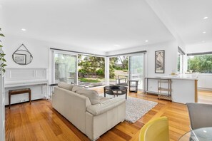 A modern living space with a sofa, a dining table, and a kitchen area.
