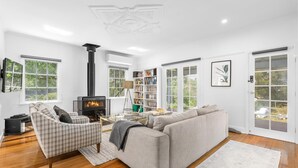 A spacious living room with a fireplace, a sofa, a chair, and a bookshelf.