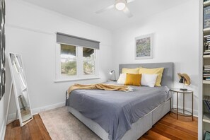 A bedroom with a bed, a window, a ceiling fan, and a bookshelf.