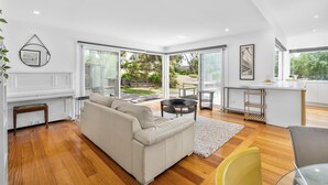 A modern living room with a sofa, a coffee table, and a dining area with a table and chairs.