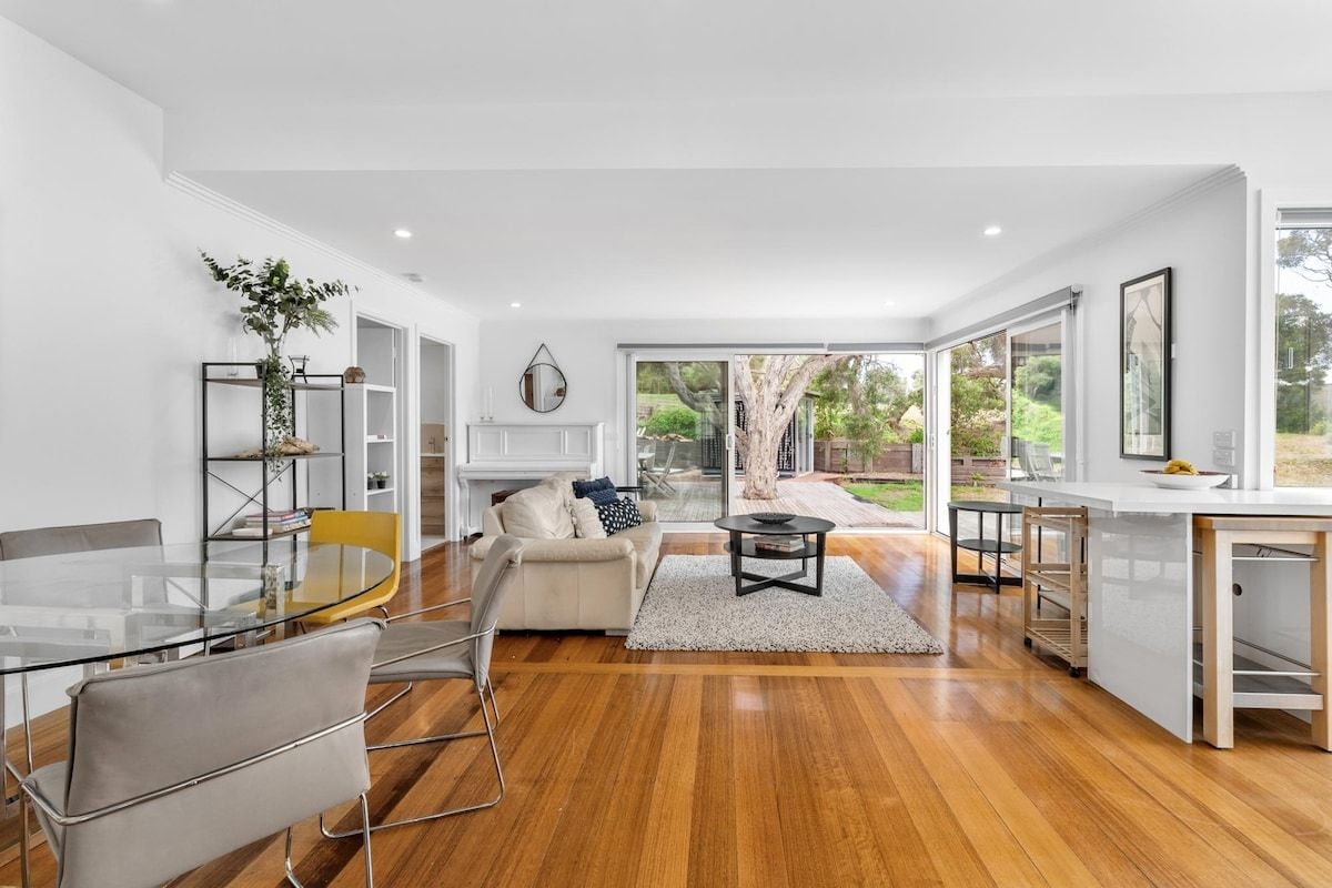 A modern living room with a glass dining table, a sofa, and a coffee table.