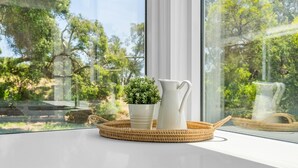 A window sill with a white pitcher, a small potted plant, and a woven basket.