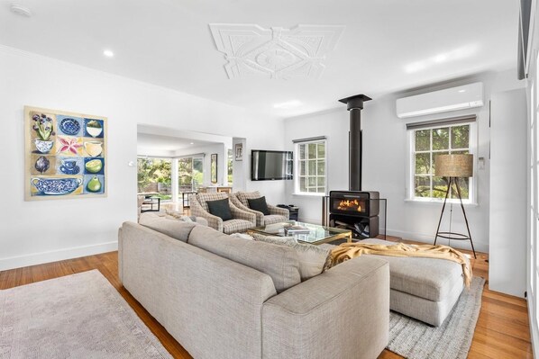 A modern living room with a fireplace, comfortable seating, and a large window.