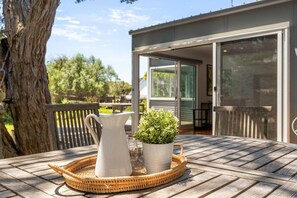 A wooden deck with a table, a white pitcher, and a potted plant.