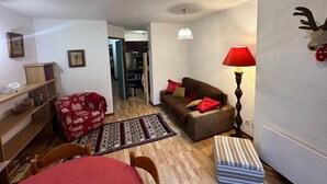 Un espace de vie compact comprenant un coin repas, un canapé, une lampe et une tête de renne décorative accrochée au mur.