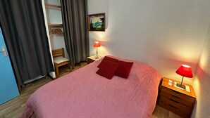 Une chambre à coucher avec un lit, deux lampes de chevet, une chaise, une armoire et un tableau au mur.
