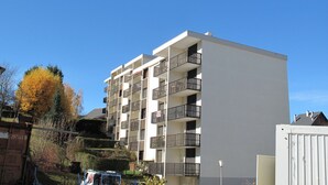 A multi-story residential building with balconies, a flat roof, and a clear blue sky.