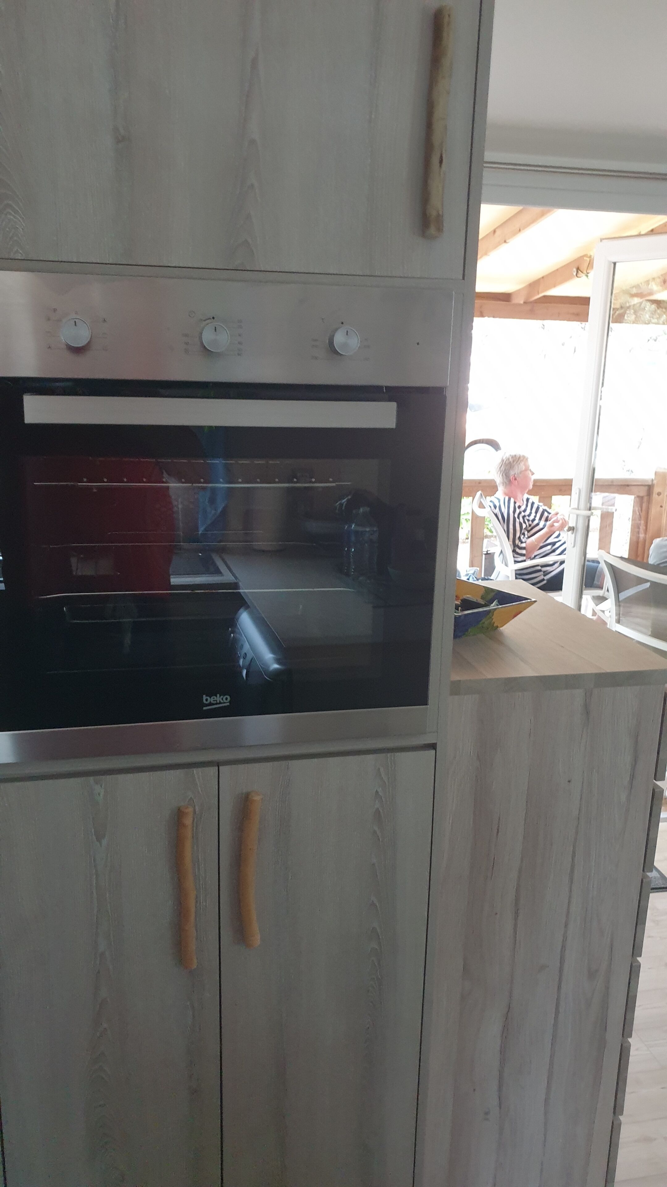 A kitchen with a built-in oven, wooden cabinets, and a window.