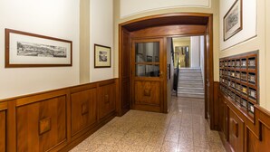 A hallway with wooden paneling, framed pictures on the walls, and a staircase in the background.