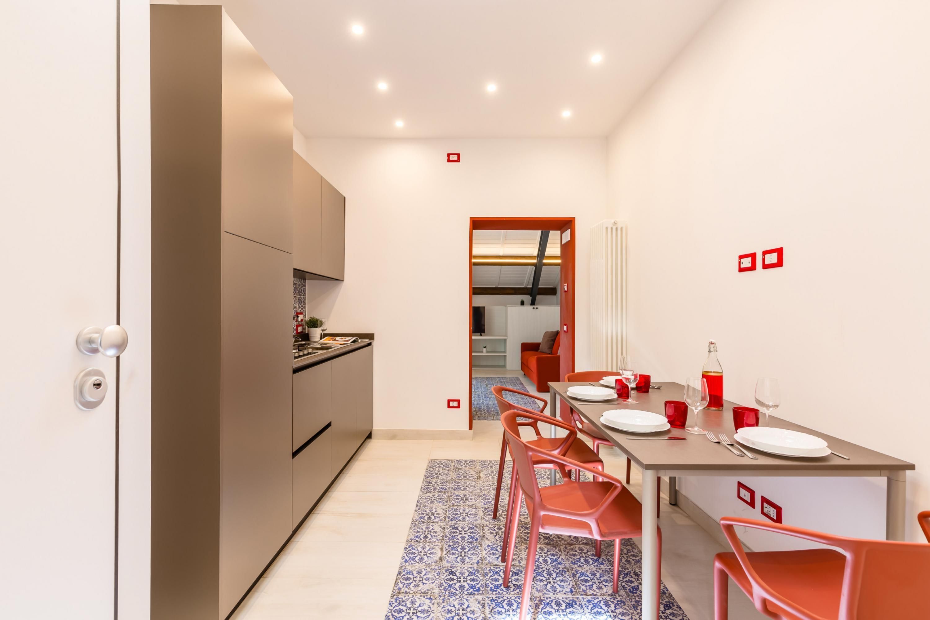 A modern kitchen with built-in appliances, a dining area with a table set for four, and a view into the living area.