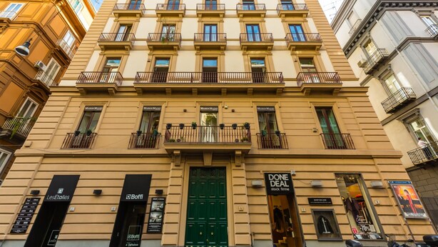 A multi-story building with a green door, multiple balconies, and storefronts including 'LesEtoiles' and 'Done Deal'.