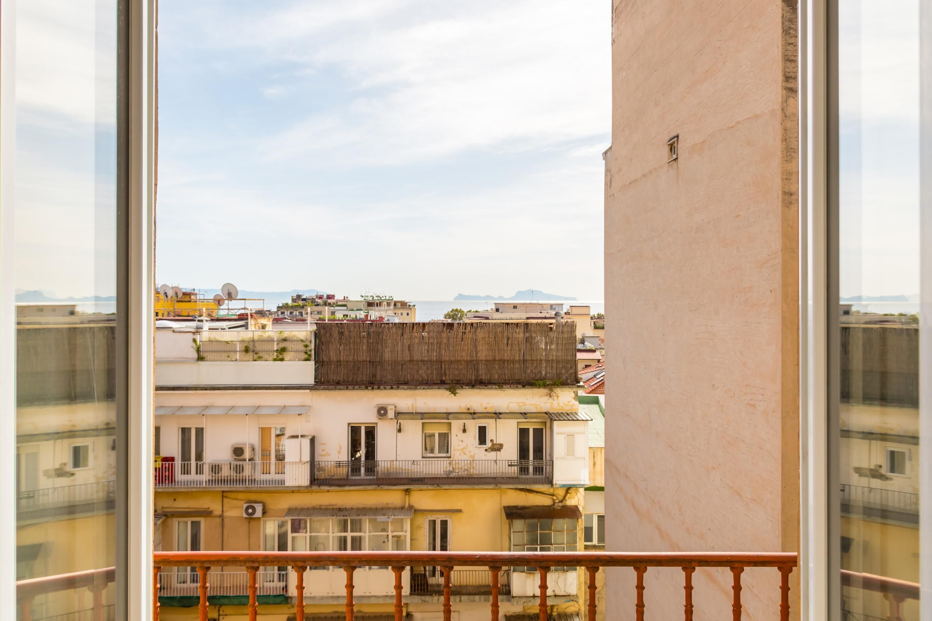 A balcony with a view of a cityscape, including buildings and a distant mountain range.