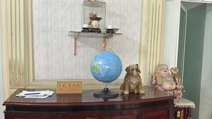 Uma receção com um globo, uma placa a indicar "Lê Tân Reception" e uma estátua.