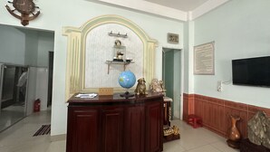 Bancada de recepção com globo, relógio e placa com a inscrição 'Lê Tân Reception'.