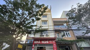 Um edifício com uma placa vermelha, uma motocicleta estacionada na frente e uma pessoa perto da entrada.