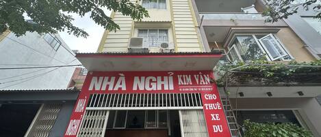 Un edificio con un letrero rojo y blanco, una entrada con reja y una escalera que lleva a los pisos superiores.