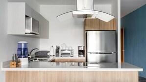A modern kitchen with a central island, stainless steel appliances, and wooden cabinetry. - Apartments near the beach pool and gym (Playa del Carmen)