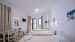 Quarto de hotel com duas camas, uma mesa, uma cadeira, uma televisão e uma janela com cortinas.