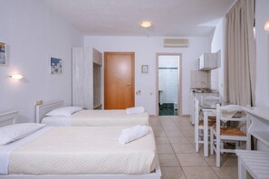 Een hotelkamer met twee bedden, een badkamer, een kleine keukenhoek en een zithoek met een tafel en stoelen.
