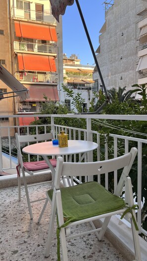 Enjoy a peaceful retreat on this balcony with a round table and two chairs, surrounded by lush greenery and the cityscape.