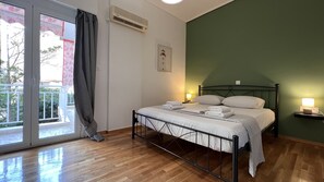 Relax in a clean and modern space with a large bed, bedside table, and sliding glass door leading to a balcony with an outdoor view.