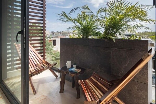 A balcony with wooden furniture, a small table, and a potted plant.