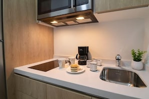 A modern kitchen with a stainless steel sink, a coffee maker, and a potted plant on the counter.