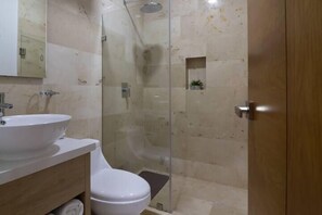 A bathroom with a sink, toilet, and glass-enclosed shower.