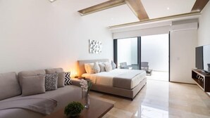 Een moderne hotelkamer met een bank, een bed, een televisie en een balkon met uitzicht.