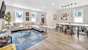 A modern living room with a sofa, coffee table, and dining area with chairs. - 2 King Beds | Sauna, Hot Tub & Pickleball Court (Cleveland)