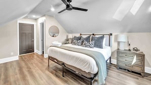 Un dormitorio con una cama, ventilador de techo, cómoda y una puerta.