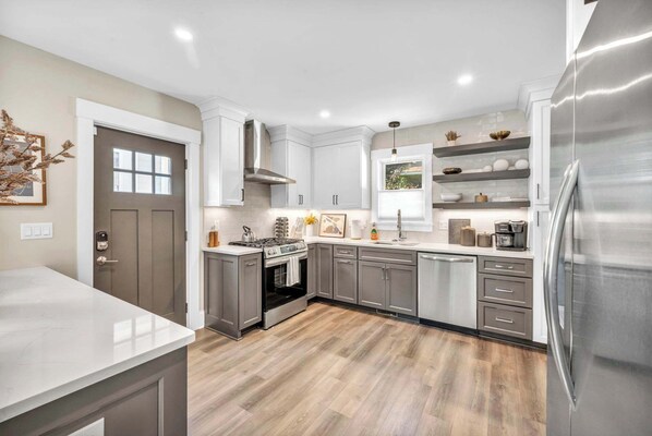 A modern kitchen with grey cabinets, a stainless steel refrigerator, and a built-in oven.