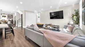 A modern living room with a grey sofa, a coffee table, and a TV mounted on the wall. - 2 King Beds | Sauna, Hot Tub & Pickleball Court (Cleveland)