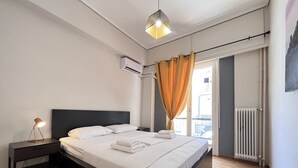 Un lit bien fait, avec du linge de lit blanc, une lampe de chevet et un appareil de climatisation fixé au mur.