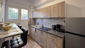 Une cuisine moderne avec des meubles en bois, un réfrigérateur en acier inoxydable, une machine à café et un coin repas comprenant une table et des chaises.