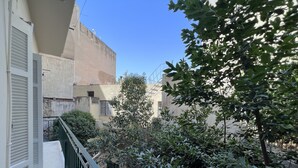 Un balcon doté d’une balustrade en métal, entouré d’une végétation luxuriante et avec des bâtiments en arrière-plan.