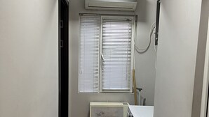 A laundry room with a washer and dryer, a radiator, and a window with blinds. - Shartava 1 (Kutaisi)