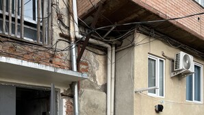 A building with exposed brickwork, a concrete ground floor, and a window with an air conditioning unit. - Shartava 1 (Kutaisi)