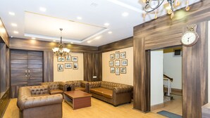 A modern living room with a sectional sofa, a coffee table, and a chandelier. - Hotel Blue Poppy (Gangtok)
