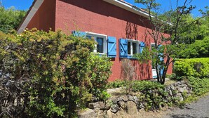 A red building with blue shutters, surrounded by greenery and a stone wall. - Cocoon de Vacances à L'espinet. Animaux de Compagnie Acceptés (Quillan)