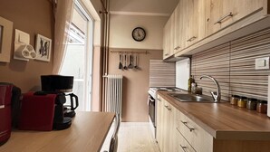 A compact kitchen with wooden cabinets, a built-in stove, a sink, and a coffee maker on the counter. - Koukaki Cozy Studio Retreat 1' from metro (Athina)