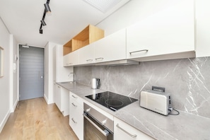 A modern kitchen with white cabinetry, a built-in oven, a stovetop, and a toaster.