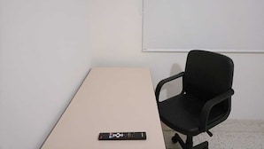 A conference room with a beige table, a black office chair, and a remote control on the table.