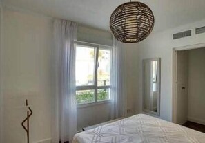 A bedroom with a bed, a window with curtains, a hanging light fixture, and a door. - Sunny Claudia´s garden Calaceite (Torrox Costa)
